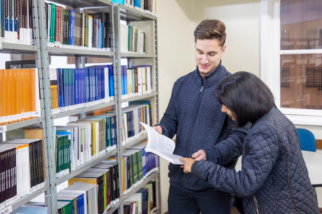 Tutor e aluna consultam livros de Administração na sala de tutoria da FAAC
